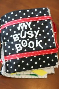 a black and white polka dot book sitting on top of a wooden table next to a red ribbon