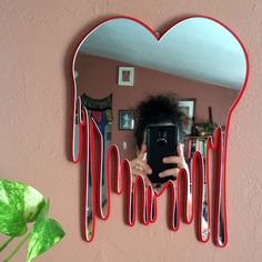a woman taking a selfie in front of a mirror with red drips on it