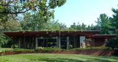 a modern house in the middle of a grassy area with trees and bushes surrounding it