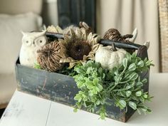 a wooden box filled with fake flowers and an owl figurine sitting on top of it