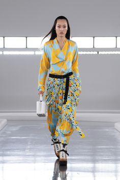 a model walks down the runway in a yellow and blue outfit