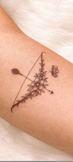 a woman's arm with a flower and arrow tattoo on it