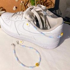 a pair of white sneakers with yellow smiley faces on them and a beaded bracelet