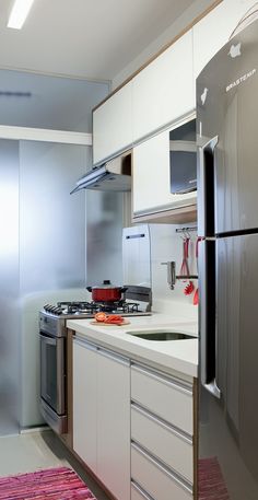 a kitchen with stainless steel appliances and white cupboards, including a refrigerator freezer