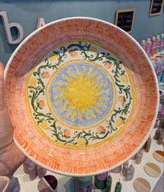 a person holding up a colorful plate with designs on it
