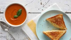 two pieces of grilled cheese and tomato soup on a plate