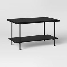 a black table sitting on top of a white floor next to a shelf with two shelves underneath it