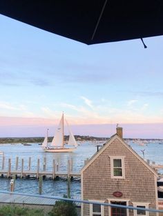 a sailboat is out on the water near a house and dock at sunset or dawn