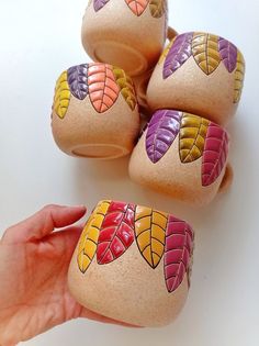 a hand is holding some rocks with leaves painted on them