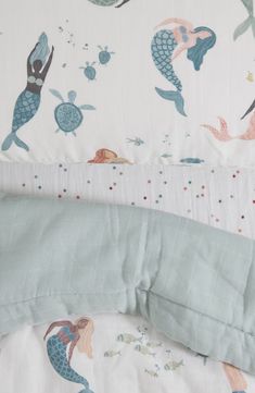 an unmade bed with mermaids and sea creatures on the sheets, along with a pillow case