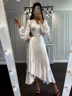 a woman taking a selfie in front of a mirror wearing a white dress and black heels