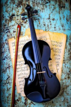 an old violin sitting on top of music sheets