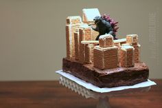 there is a cake that looks like a castle with a godzilla on top and bricks in the middle