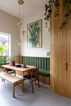 a dining room table and bench with plants on the wall