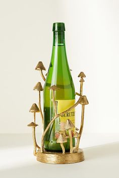 a bottle that is sitting in front of a glass vase with mushrooms on it and a corkscrew