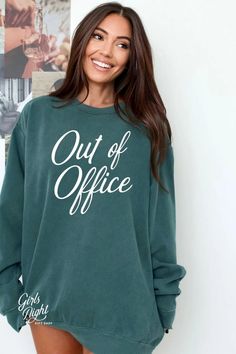 a smiling woman wearing a green sweatshirt with the words out of office printed on it