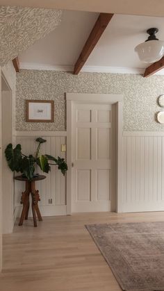 a living room with white walls and wood flooring on the floors, along with a rug that has been placed in front of an open door