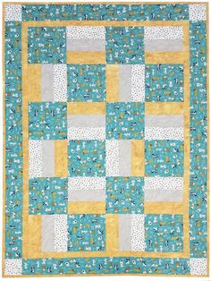 a blue and yellow patchwork quilt with white flowers on the border, in front of a