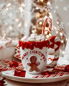 a cup filled with marshmallows on top of a plate next to a christmas tree