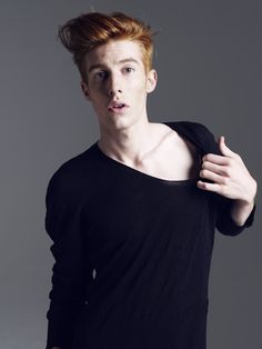 a young man with red hair is posing for the camera while wearing a black shirt