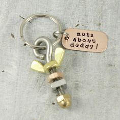 a metal keychain with two nuts and a tag that says nuts about daddy