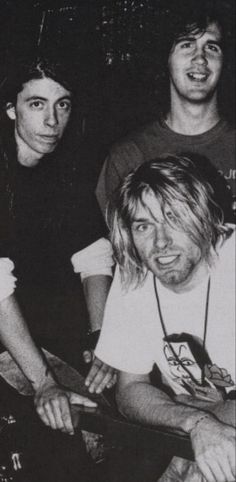 black and white photograph of three men standing next to each other in front of a table