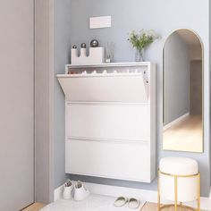 a white cabinet sitting next to a mirror in a room with shoes on the floor