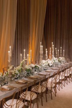 a long table is set up with white flowers and greenery for an elegant dinner