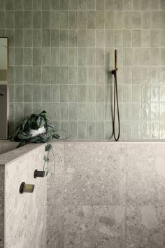 a tiled bathroom with a shower head and hand held faucet next to it