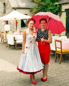 two women standing next to each other with umbrellas over their heads and tables in the background