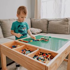 a young boy playing with legos on a coffee table in his living room,