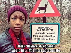 a woman standing in front of a sign that says, beware of falling deer leopards conceal their unfinished food in the tops of trees