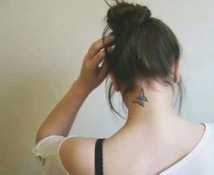 a woman with a small butterfly tattoo on her neck and behind her head is a white wall