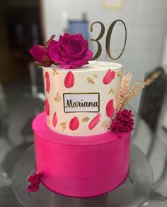 a pink and white cake sitting on top of a glass table next to a number 30 sign