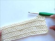 someone is crocheting the edge of a piece of white yarn with a green needle