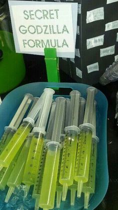 several test tubes are in a blue bowl on a table next to a sign that says secret gozilla formula