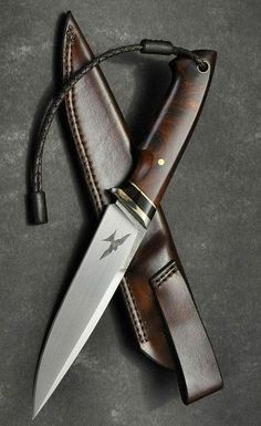 a knife is laying on top of a brown leather sheath with a black star design