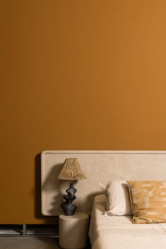a bed with two lamps on either side of it and an orange wall in the background