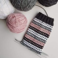 several balls of yarn and knitting needles on a white surface with one ball of yarn in the foreground