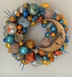 a christmas wreath with ornaments hanging from it's sides and a crescent on the front