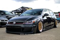 a black car with gold rims parked next to other cars