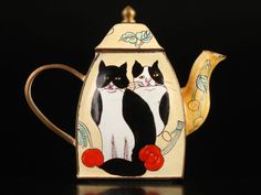 a teapot with two cats painted on it