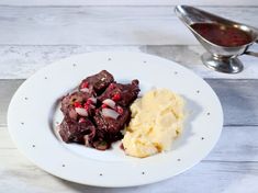 a white plate topped with meat and mashed potatoes