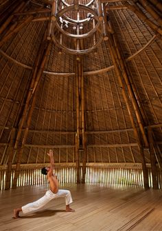 a man is doing yoga in a large room with bamboo walls and ceilinging,