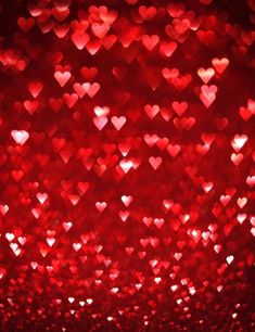 many hearts are arranged in the shape of red glitters on a dark background photo