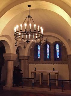 a chandelier hanging from the ceiling in a church with stained glass windows and columns