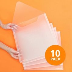 a person holding some clear plastic sheets on top of an orange surface