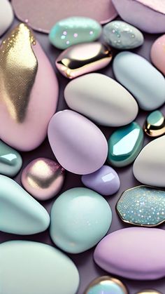 many different colored rocks and pebbles on a purple surface with gold leaf shapes in the middle