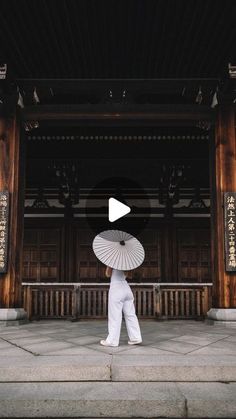 a person with an umbrella walking in front of a building