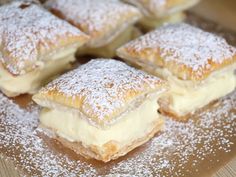 some desserts are sitting on top of a cutting board covered in powdered sugar